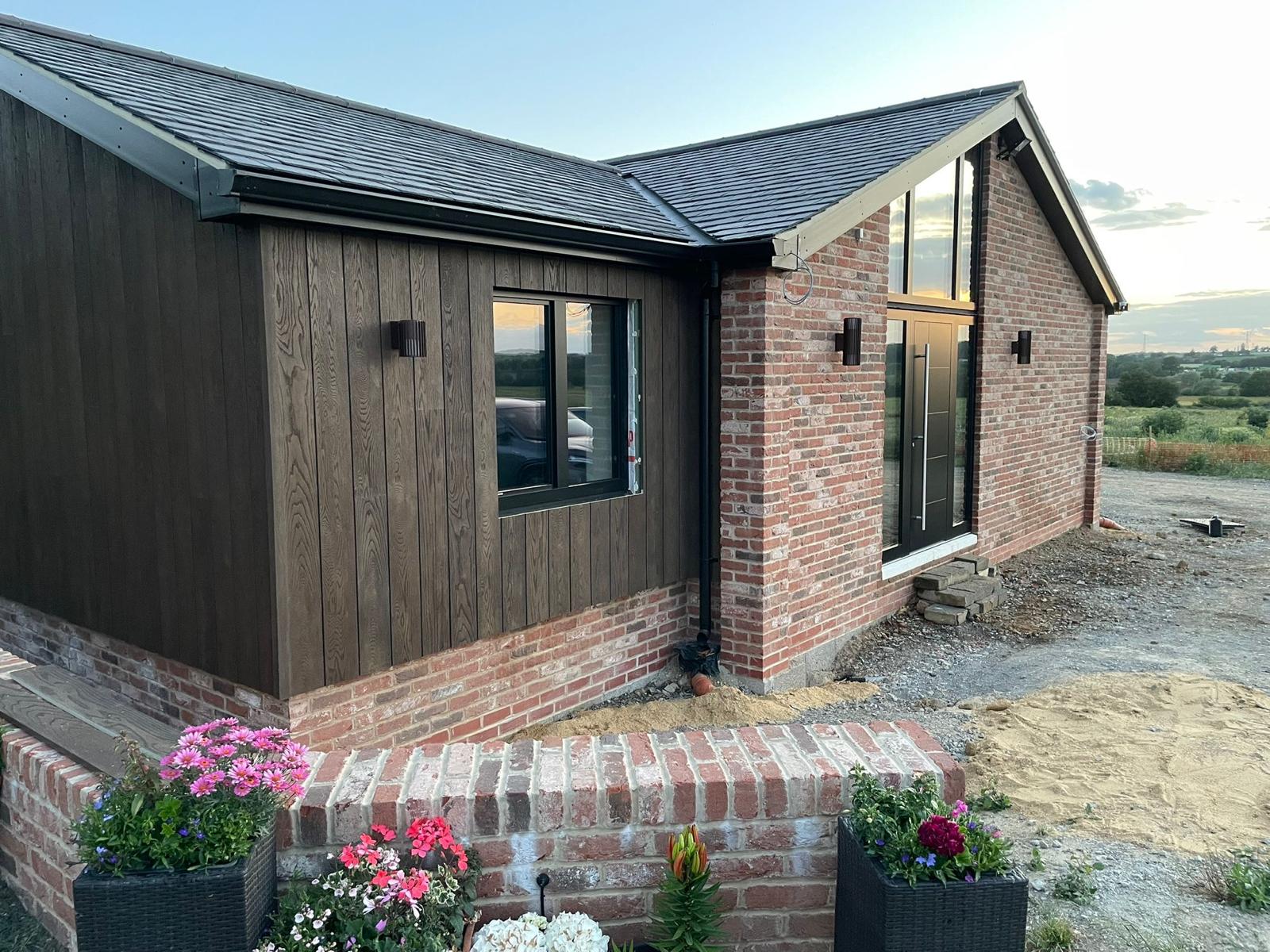 Entrance with detailed brickwork, dark timber cladding and a glazed gable