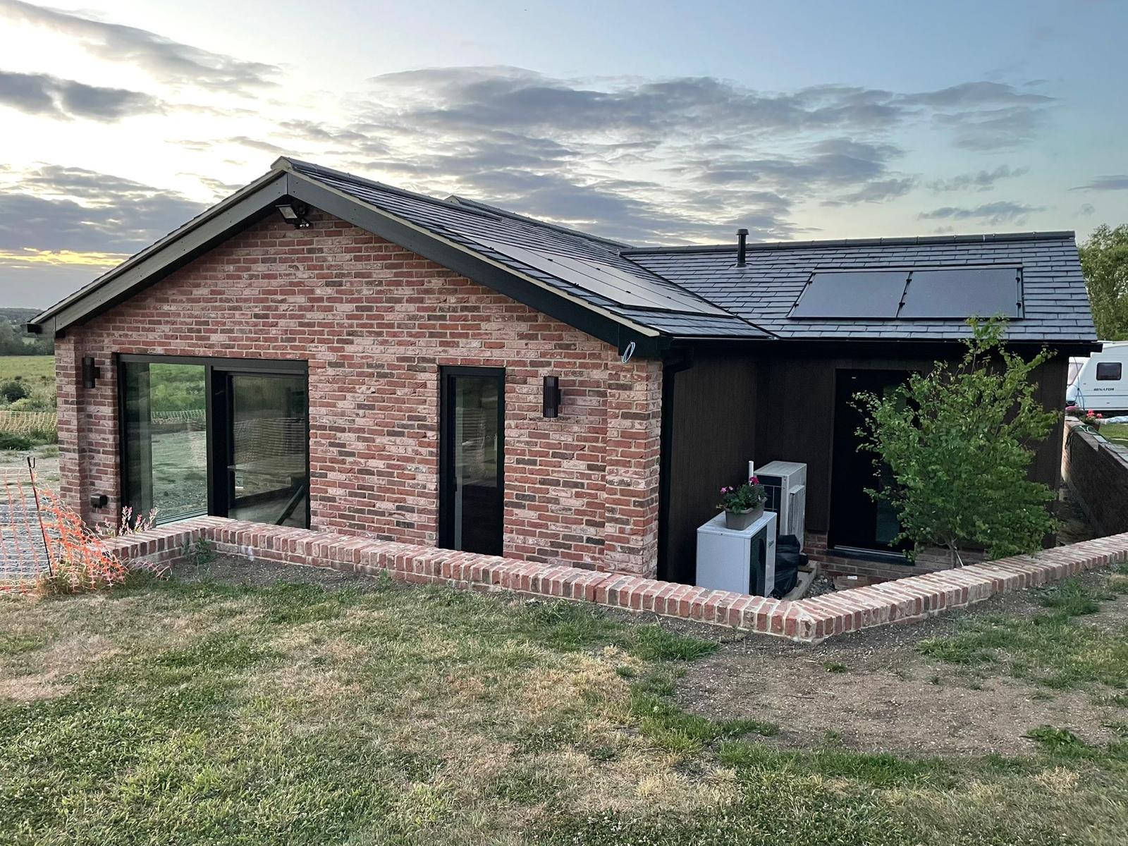 Brick and timber clad home with a slate roof and large windows